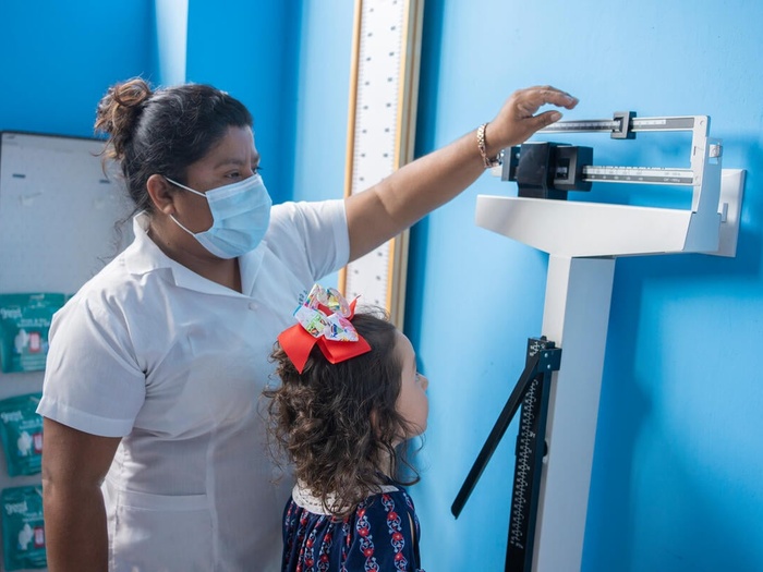 A refugee girl in Guatemala has her height and weight measured at a health facilty as part of a check up. 
