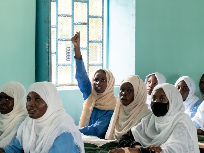 A girl raises her hand in a school classroom.