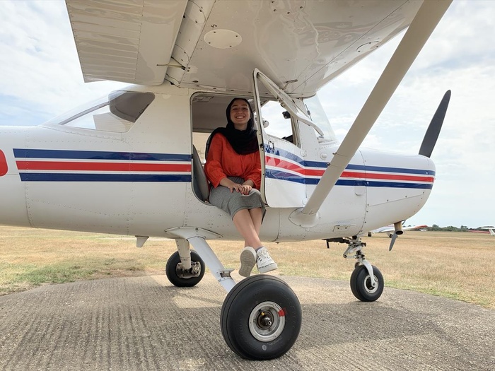 A young woman sits in a small plane's cockpit
