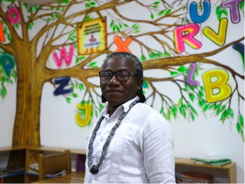 professor stands in front of wall painted with a tree in school