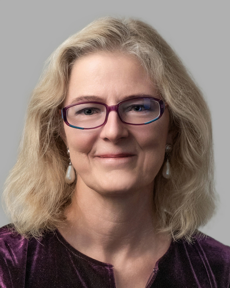 headshot of woman with shoulder length blond hair and dark rimmed glasses
