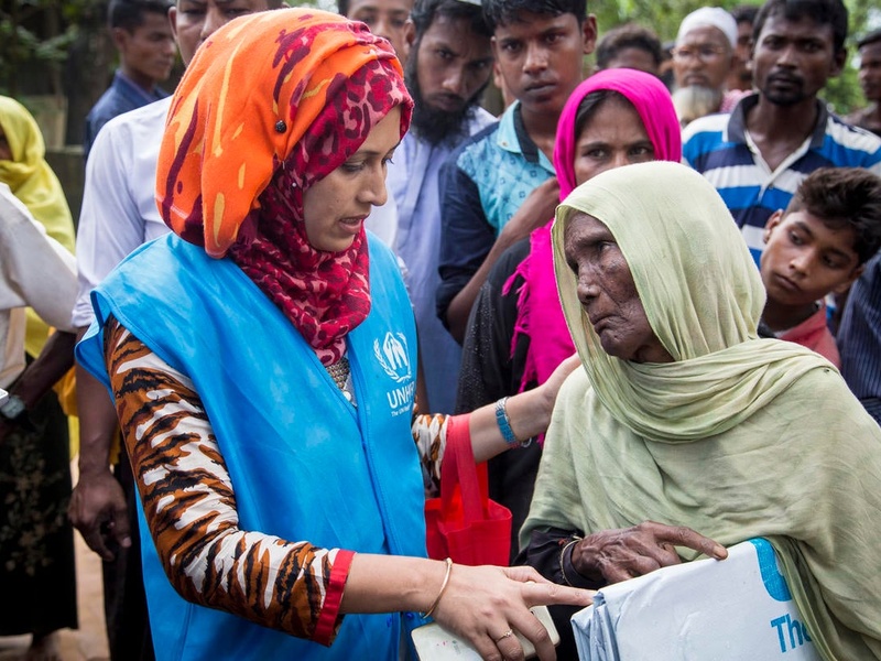 An elderly woman receives a tarpaulin from a UNHCR staff member, in Bangladesh.