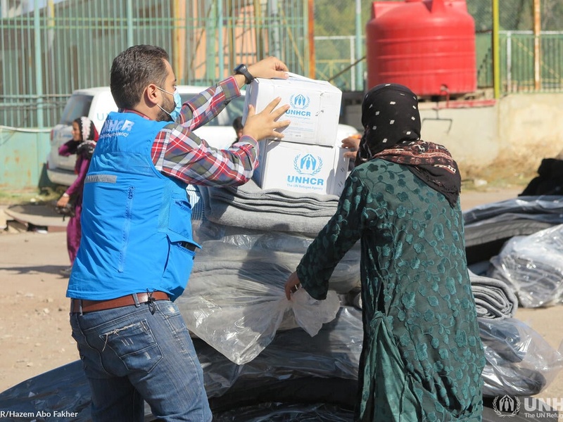 Two people unpack UNHCR boxes and blankets in Syria 
