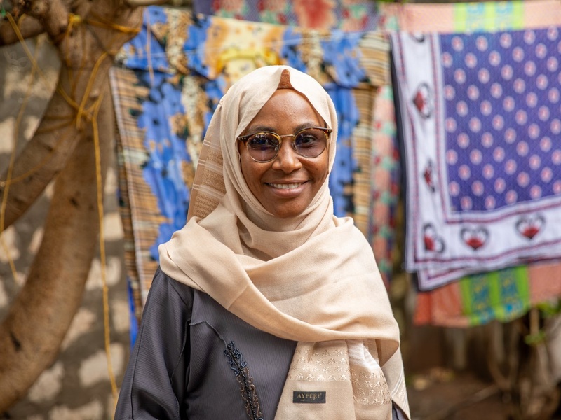 Portrait of a woman wearing glasses and a headscarf.