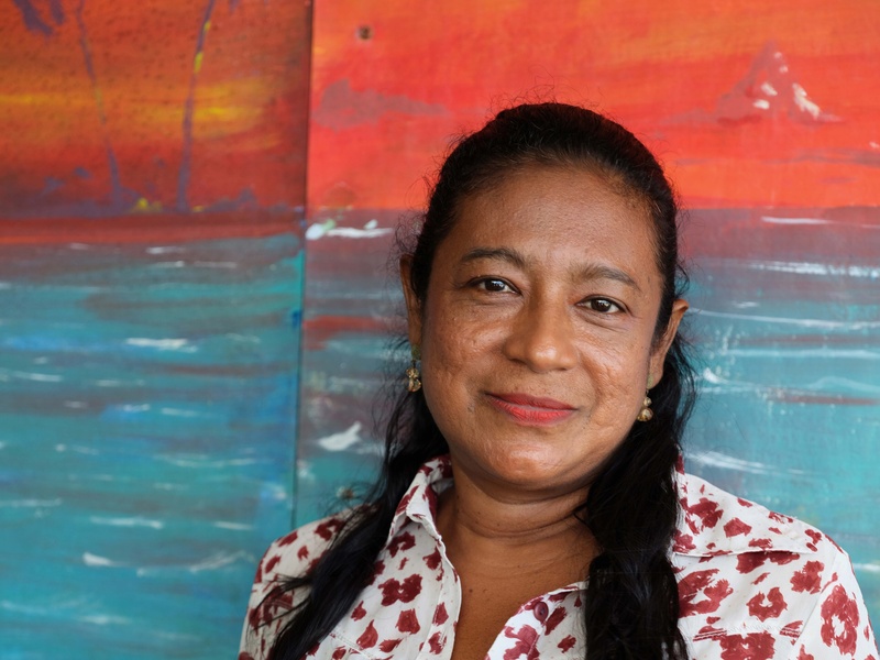 a female teacher stands in front of a blue and orange painting