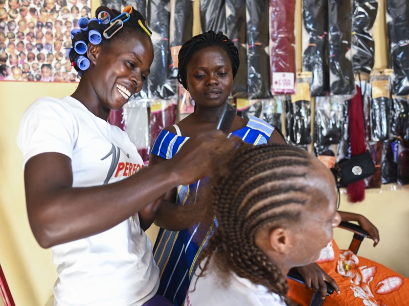 A woman braids the hair of another woman.