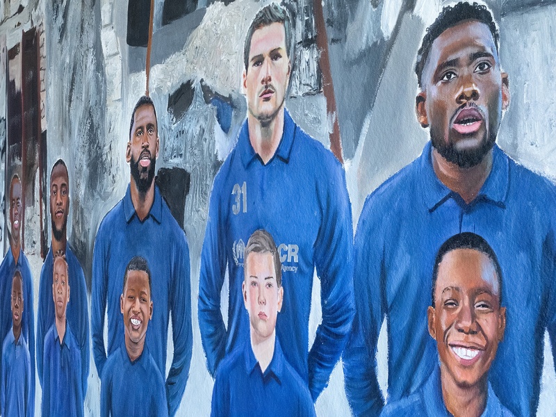 Picture of a wall painting picturing football players and kids standing in front of them