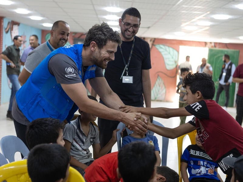 Theo James smiles and holds the hands of a young boy