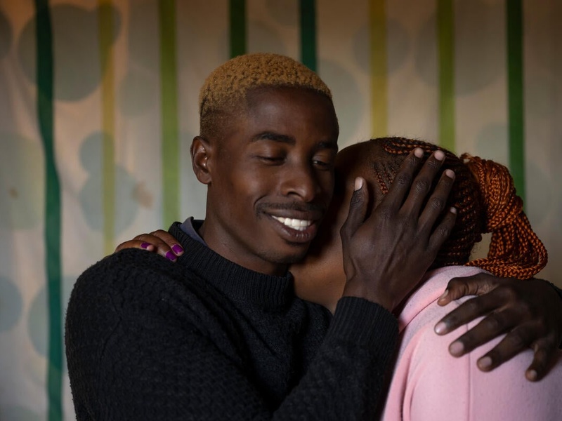 Formally stateless person Tebogo, 26, smiles as he hugs his partner, holding her face to his in a gentle embrace.
