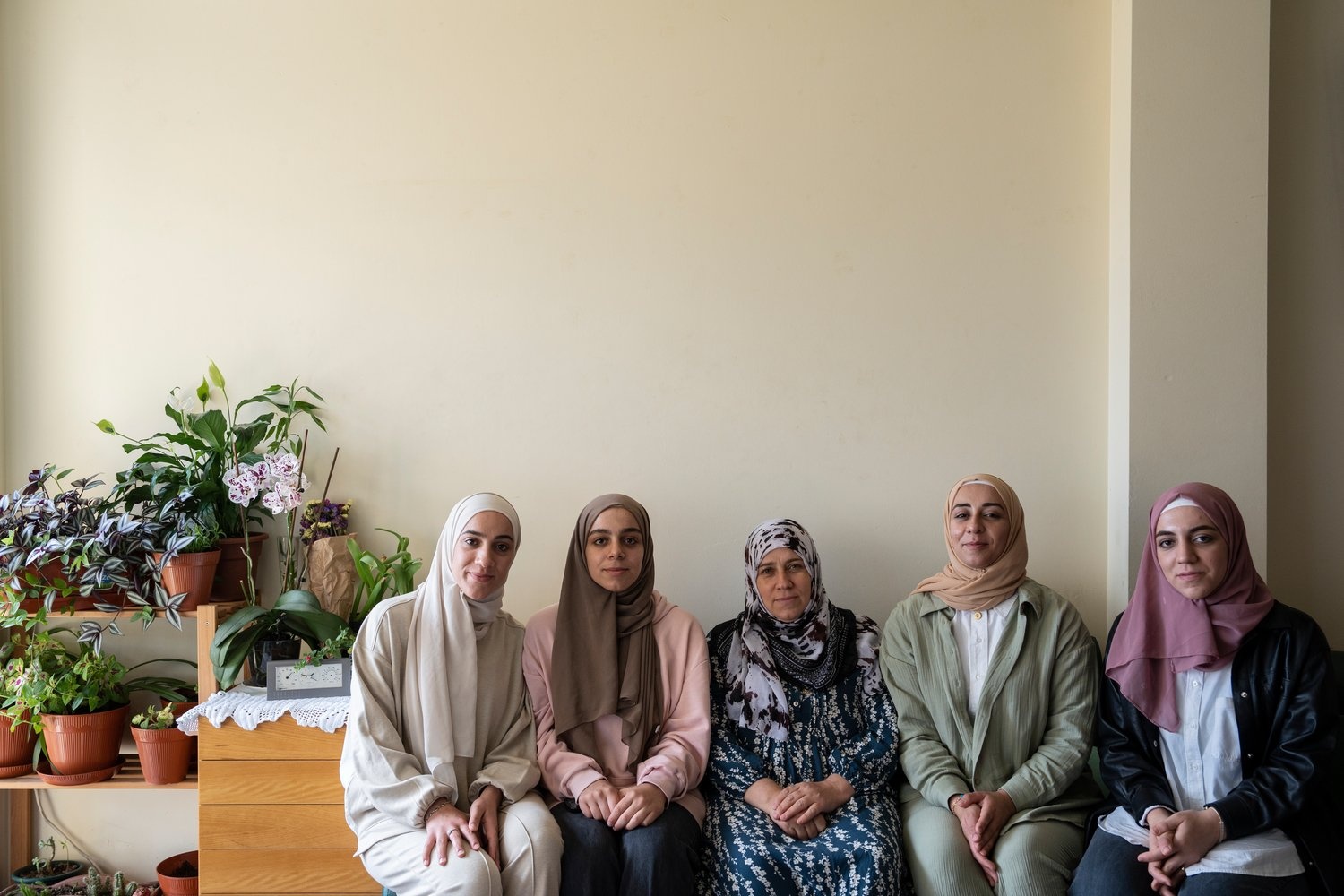 A mother sits on a couch surrounded by four of her daughters.