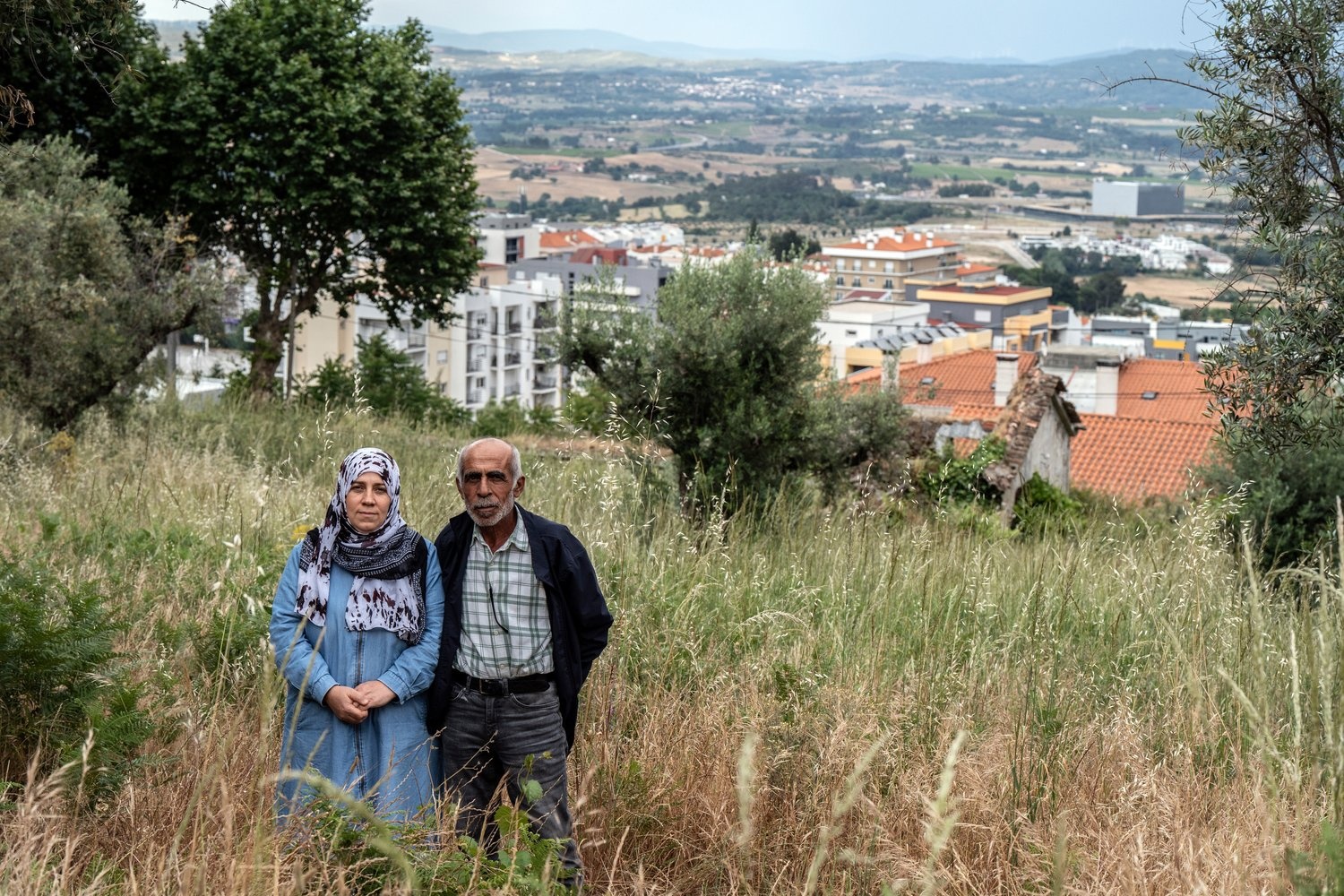 Muna and Moustafa Albakkar stand on a grassy  hillside above the town of Covilhãof 
