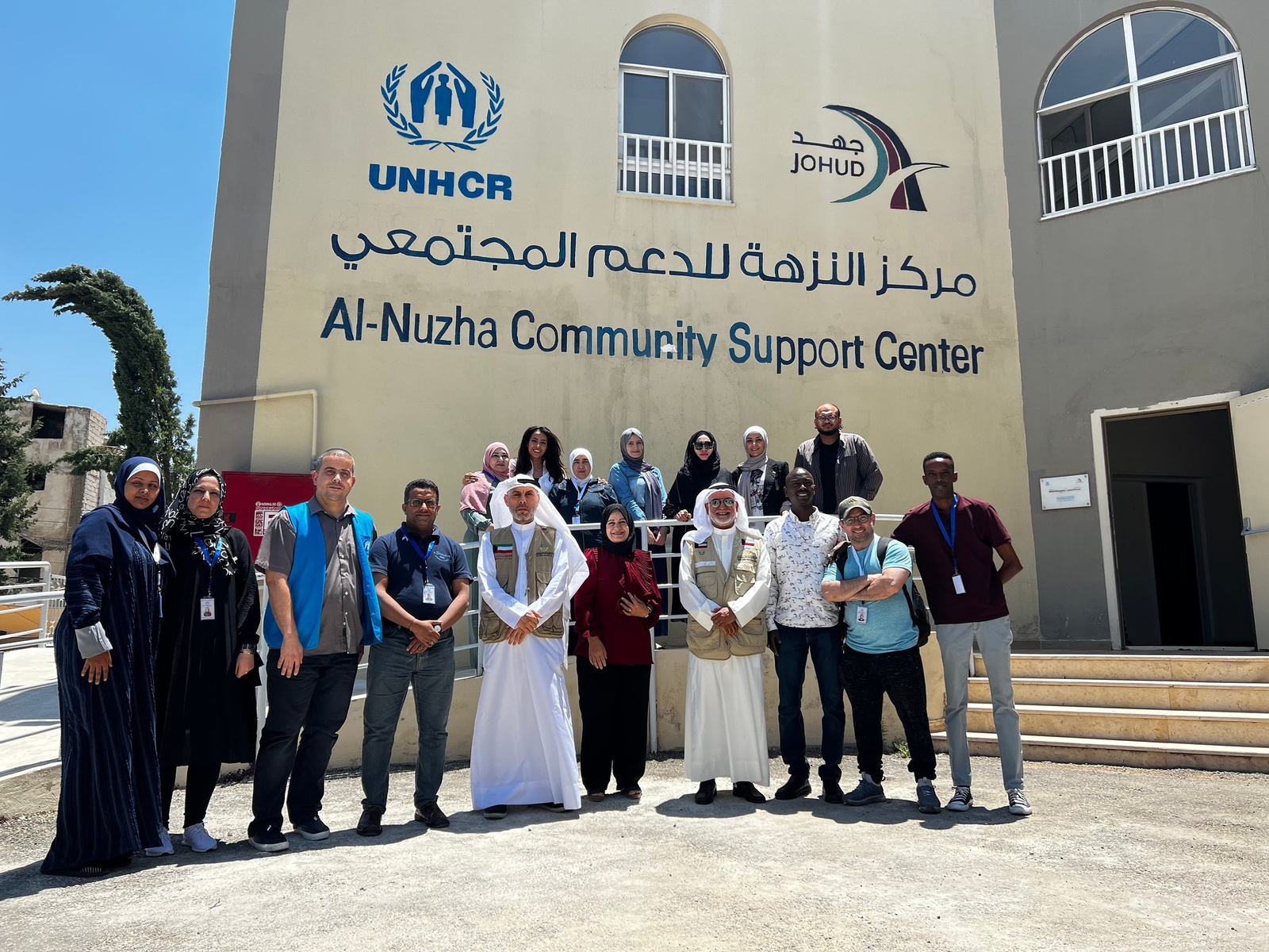 Mr. Jamal with a large group of people outside the Al-Nuzha Community Support Center on a sunny day