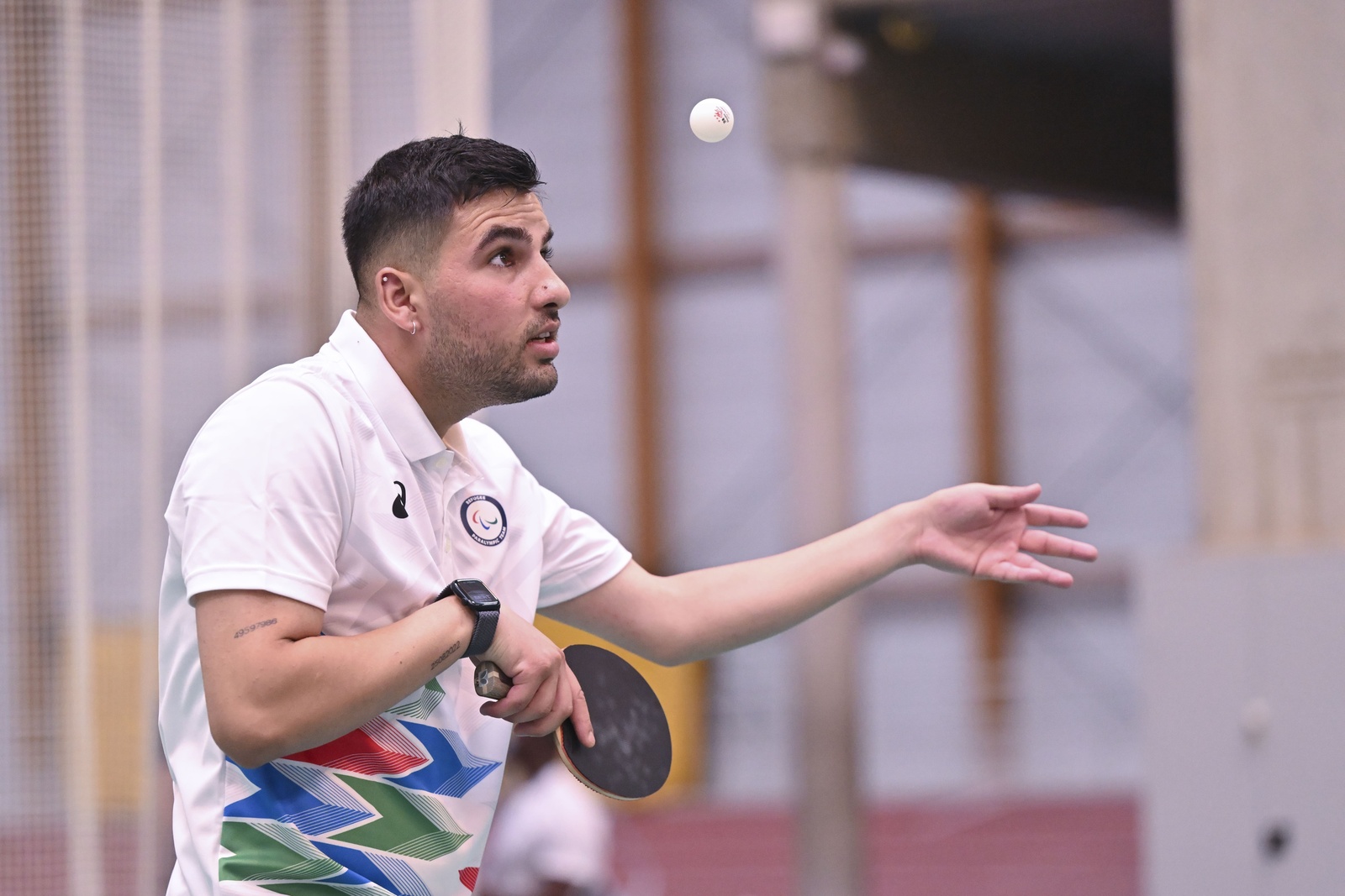 A man holds a table tennis bat with his eyes fixed on a ball