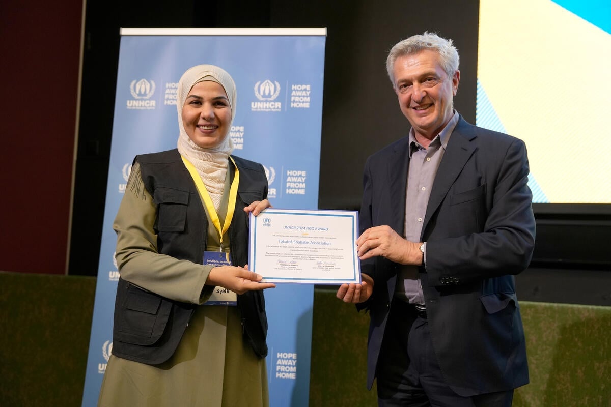 Ms. Wafaa Al Askar Al Hifel and United Nations High Commissioner for Refugees Filippo Grandi holding up an award and smiling at the camera