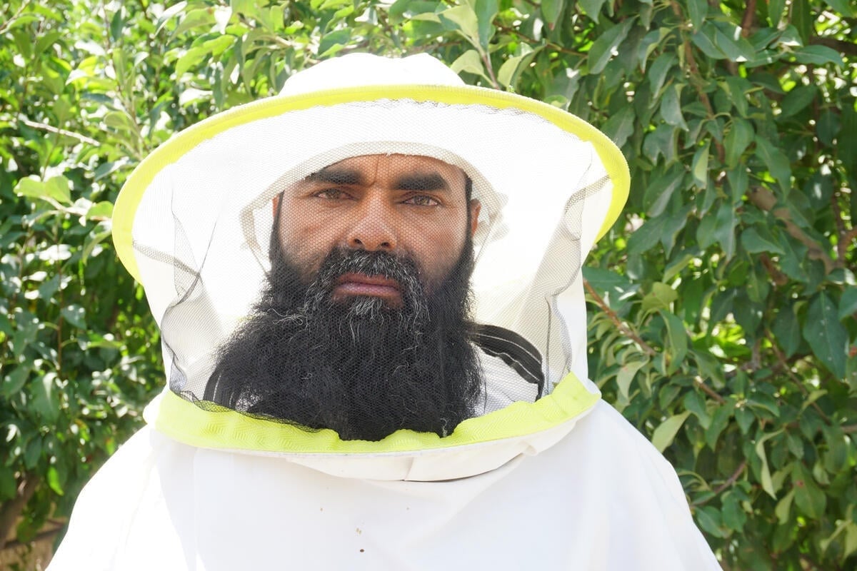 A man with beard wearing a white bee-keeping suit