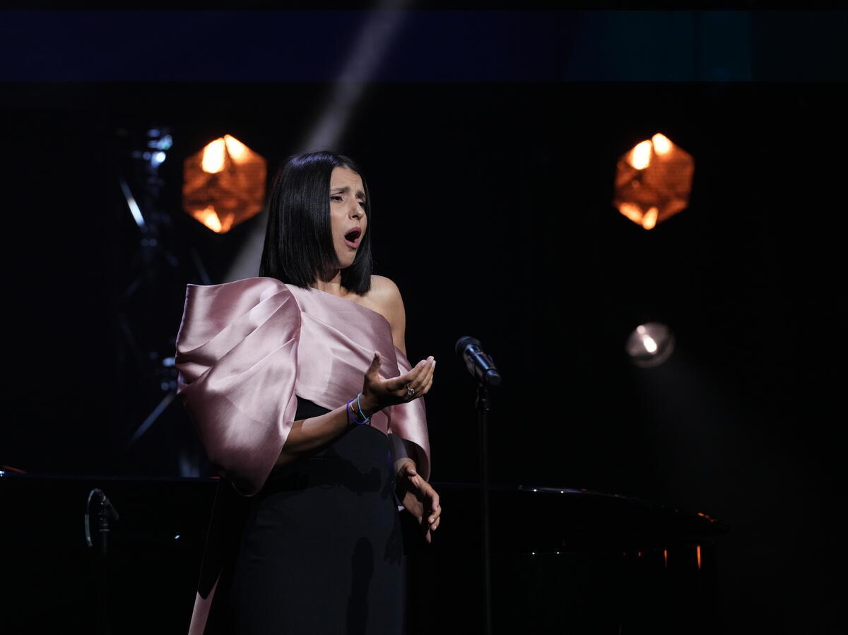 A woman in a pink evening dress sings onstage