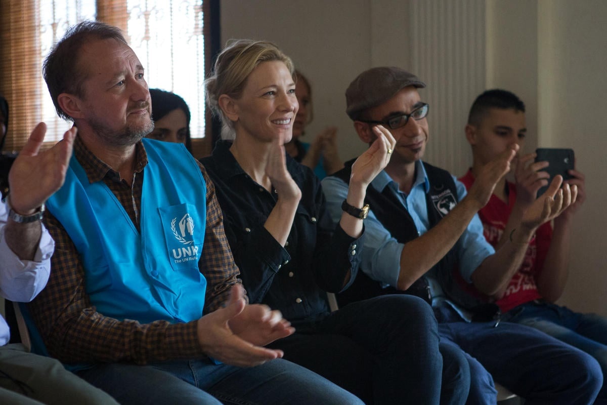 Four seated audience members smiling and clapping