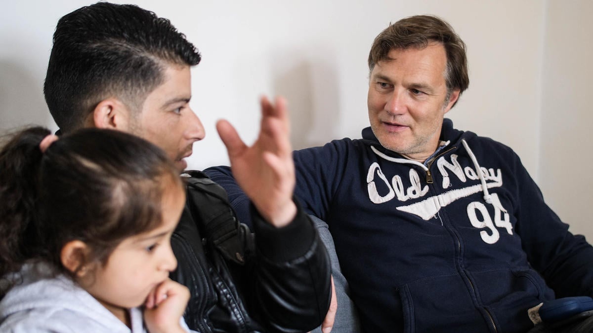 David Morrissey sits next to Jamal and his daughter.