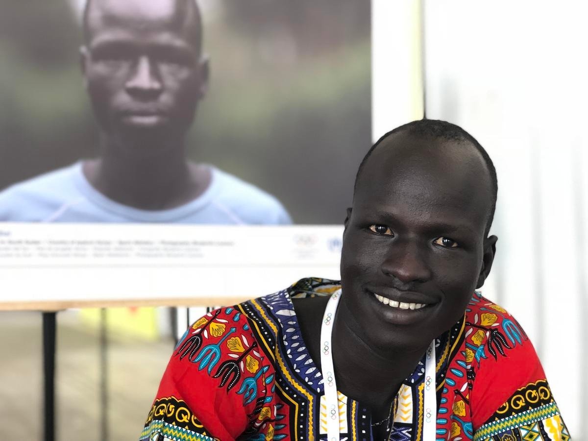 Pur Yiech Biel poses next to a photo of himself taken during the Rio 2016 Olympic Games.