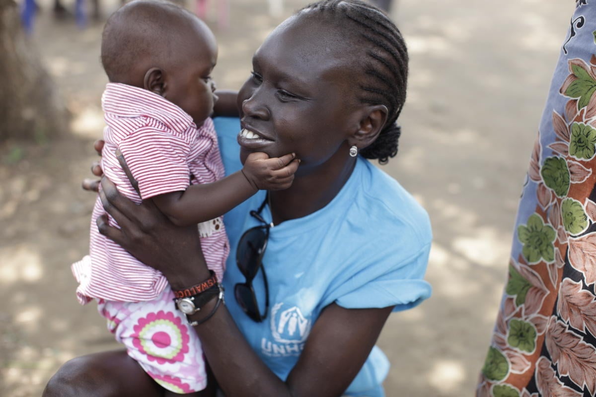Alek Wek holds a baby in her arms.