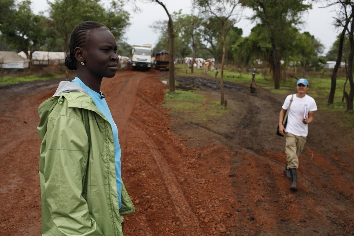 Alek Wek walks on a dirt road.