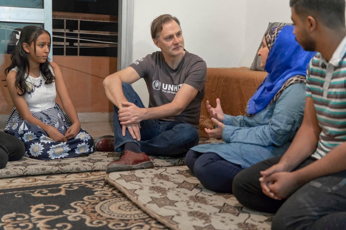 David Morrissey sits on the ground inside a house with a family of Syrian refugees.