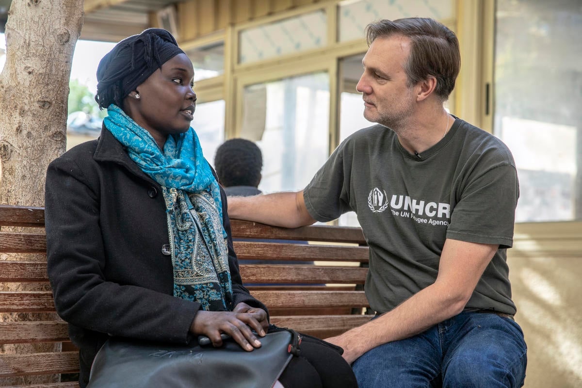 David Morrissey sits on a bench next to Aud, a South Sudanese refugee.