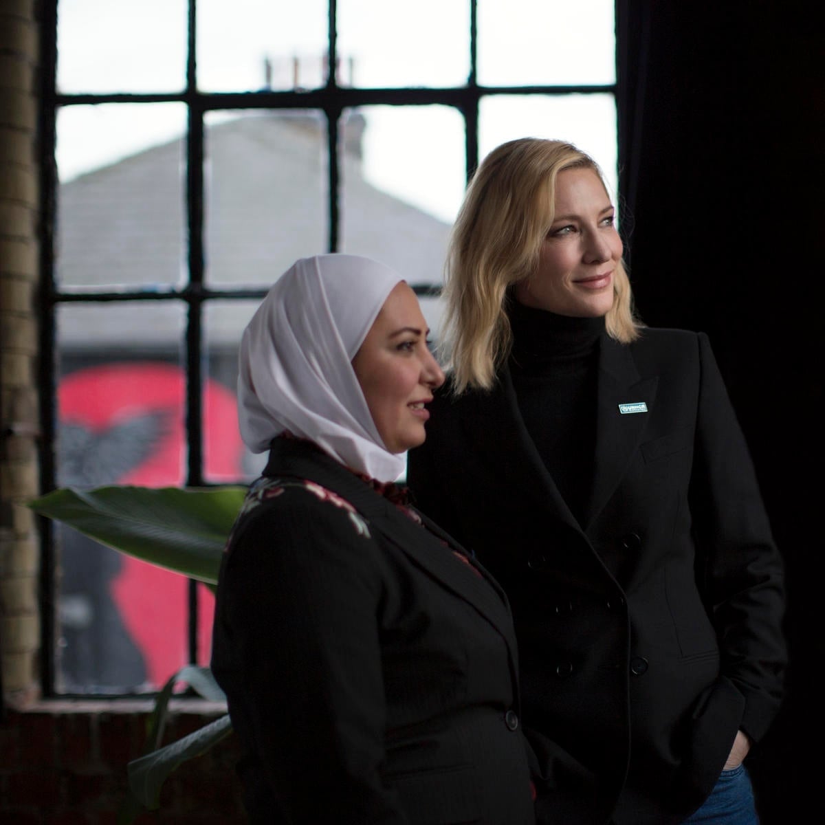 Two women pictured in front of a window, looking into the distance