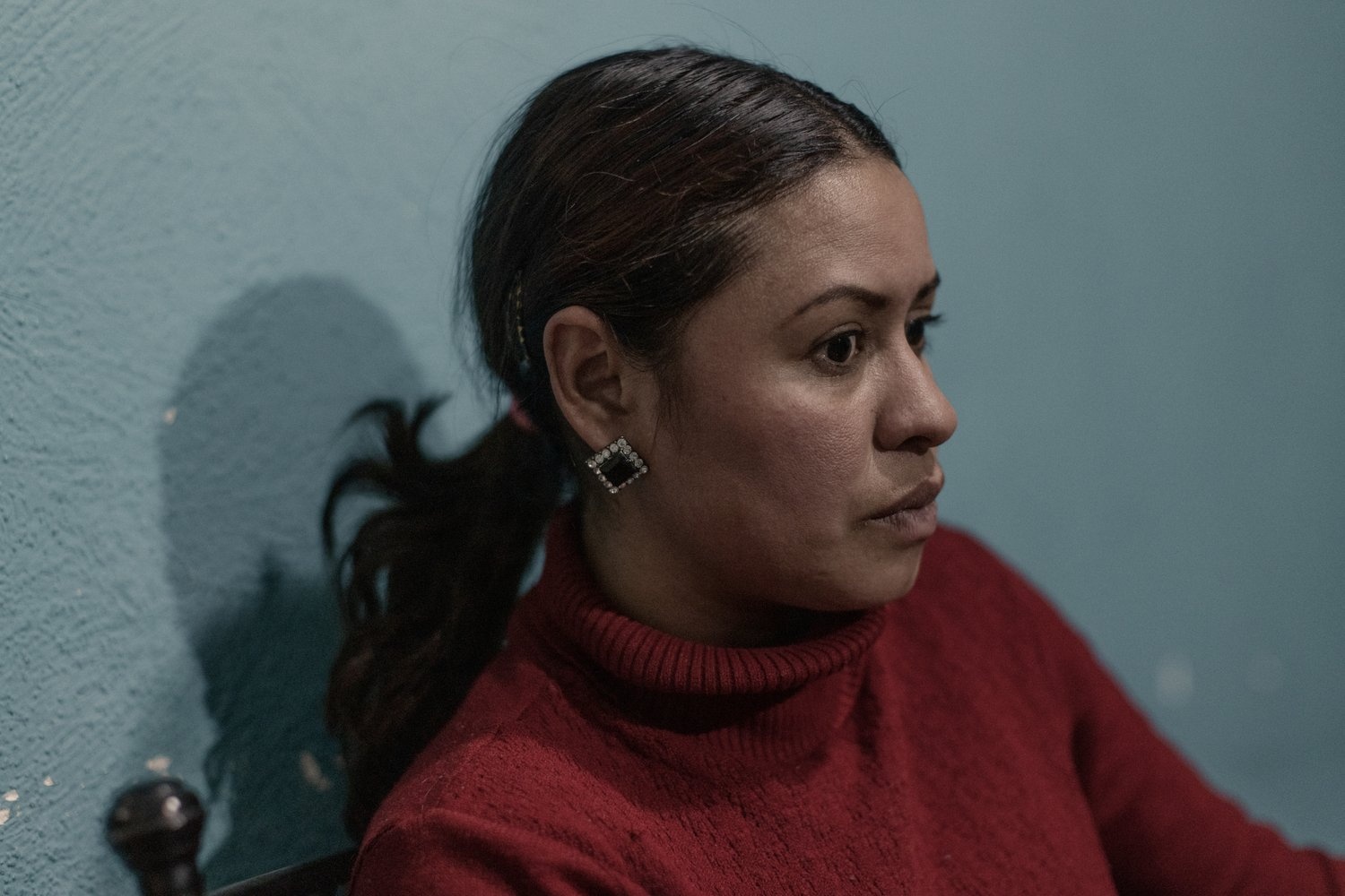 A woman in a red jumper stares into space.