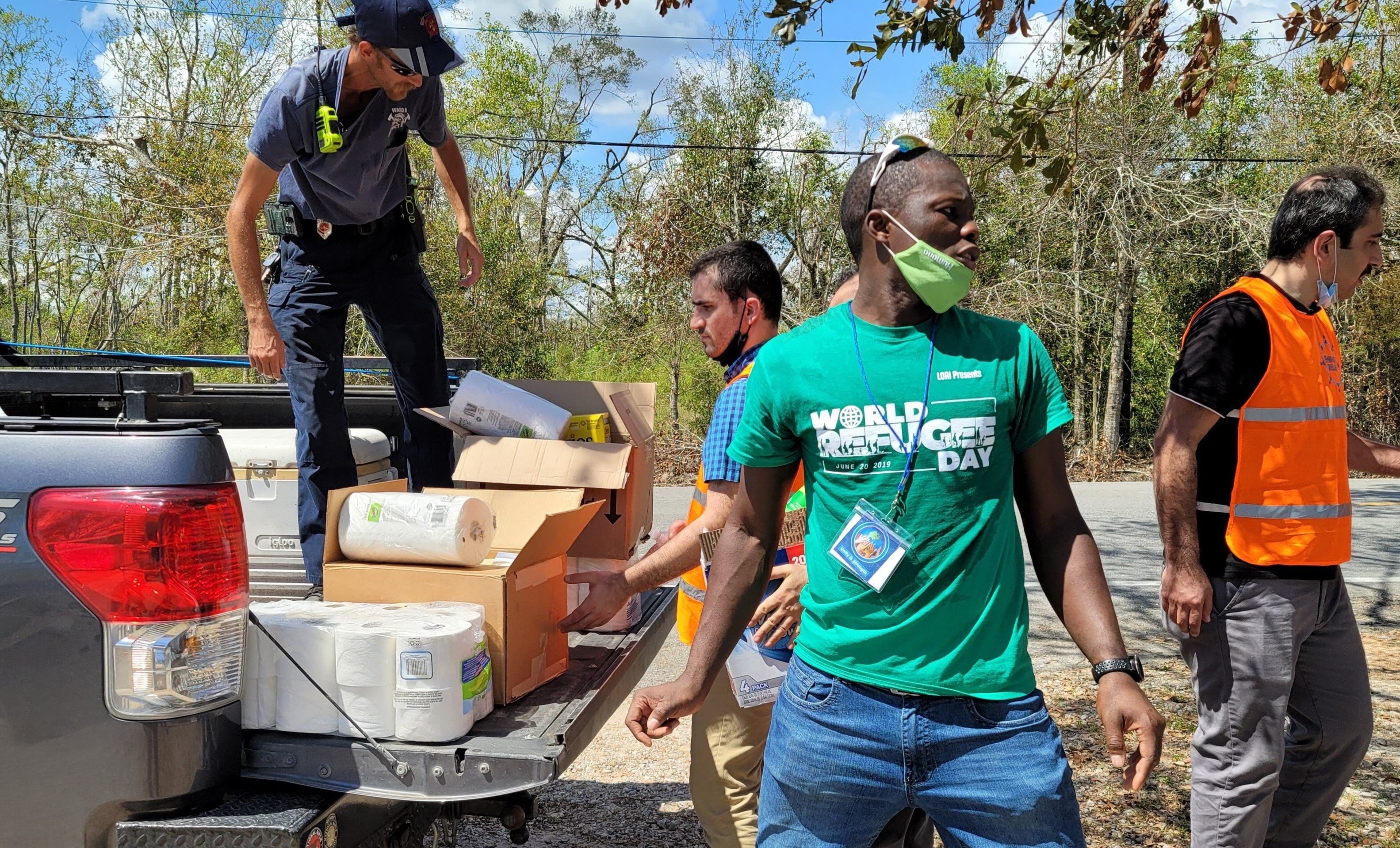 Men unload boxes of relief supplies from the back of a pickup truck.