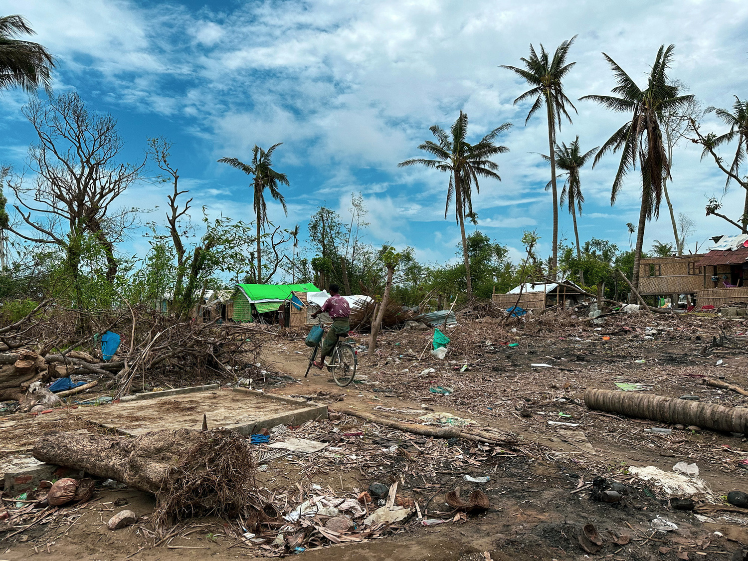 A young man cycles through a scene of destruction following a cyclone.
