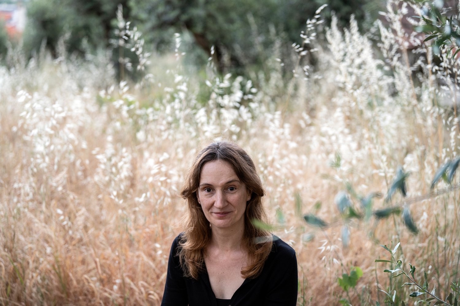 Leonor Cutileiro sits for a portrait in a field of long dry grasses.