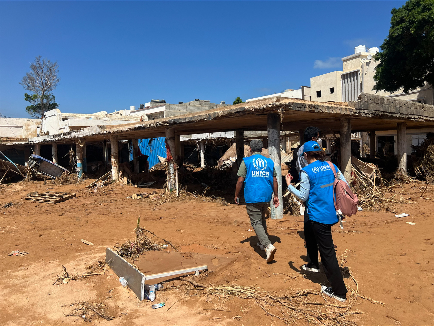 Two UN officials walk in front of a damaged building