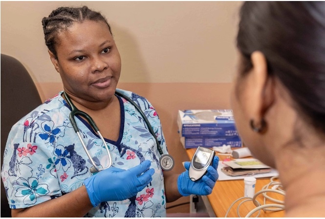 A doctor in a medical uniform with blue gloves, in front of a woman in her medical office 