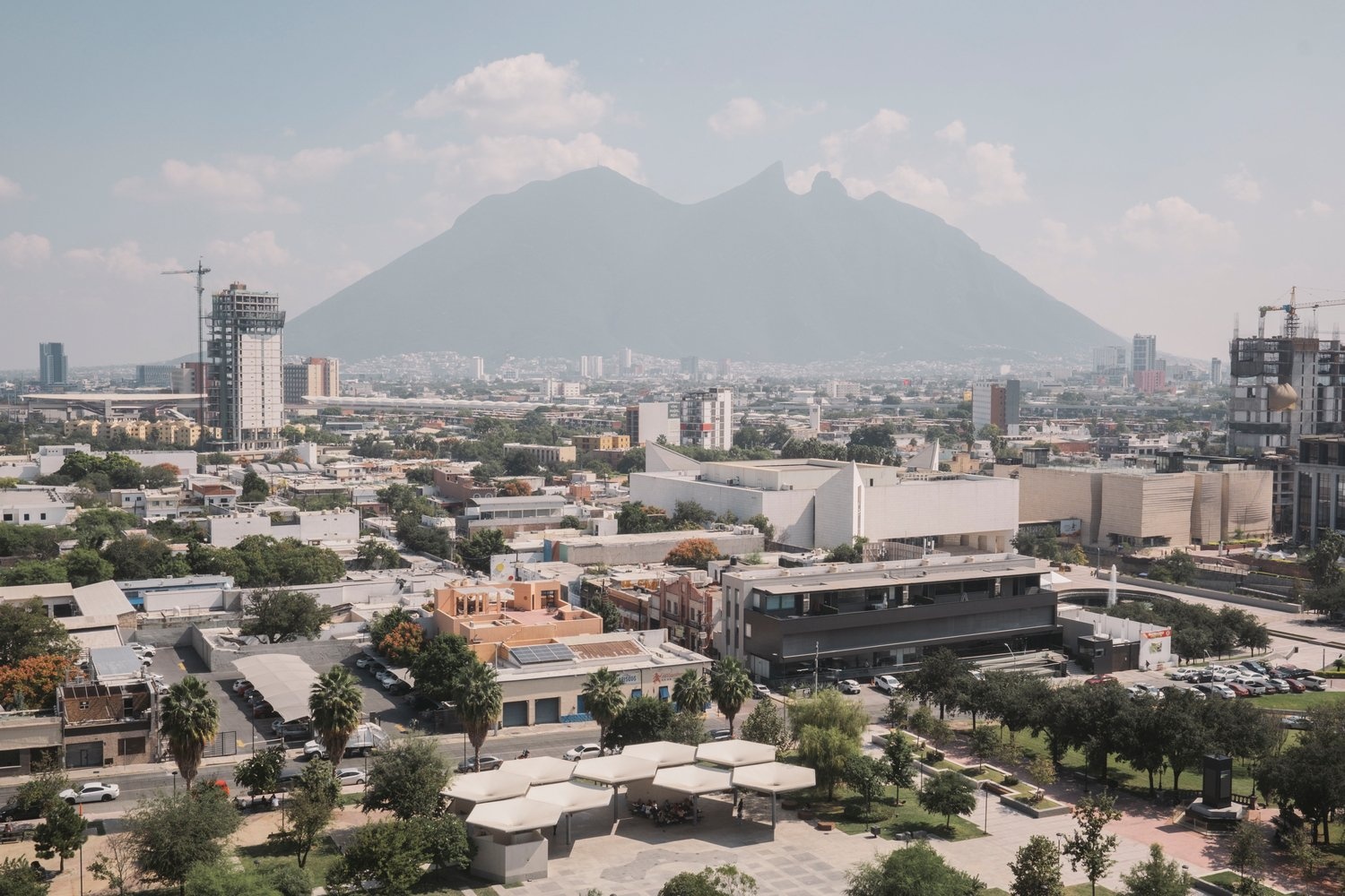 A mountain dominates the haze-filled horizon of a modern city landscape 