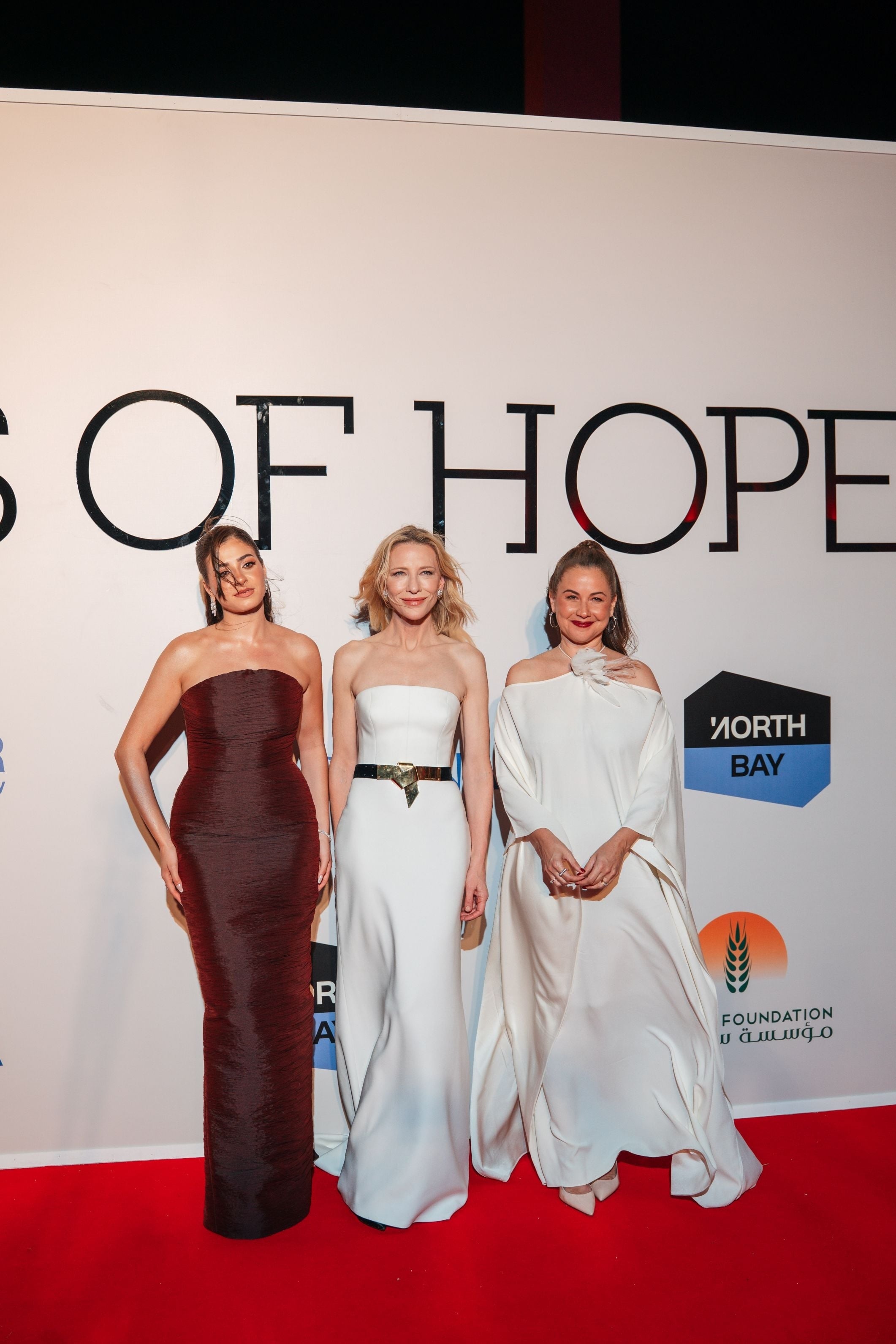 Three women pose for the camera on the red carpet.