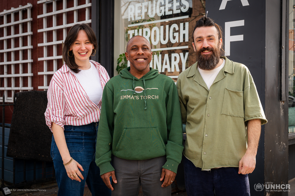 Three people standing in front of Emma's Torch Cafe.