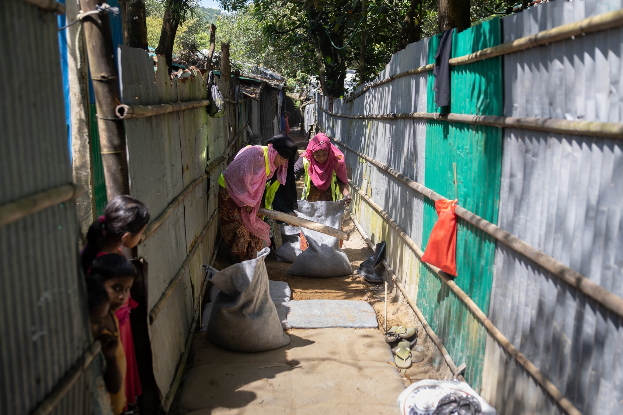 Rohingya refugee women in Cox's Bazar refugee camp working together to pave alleyways.