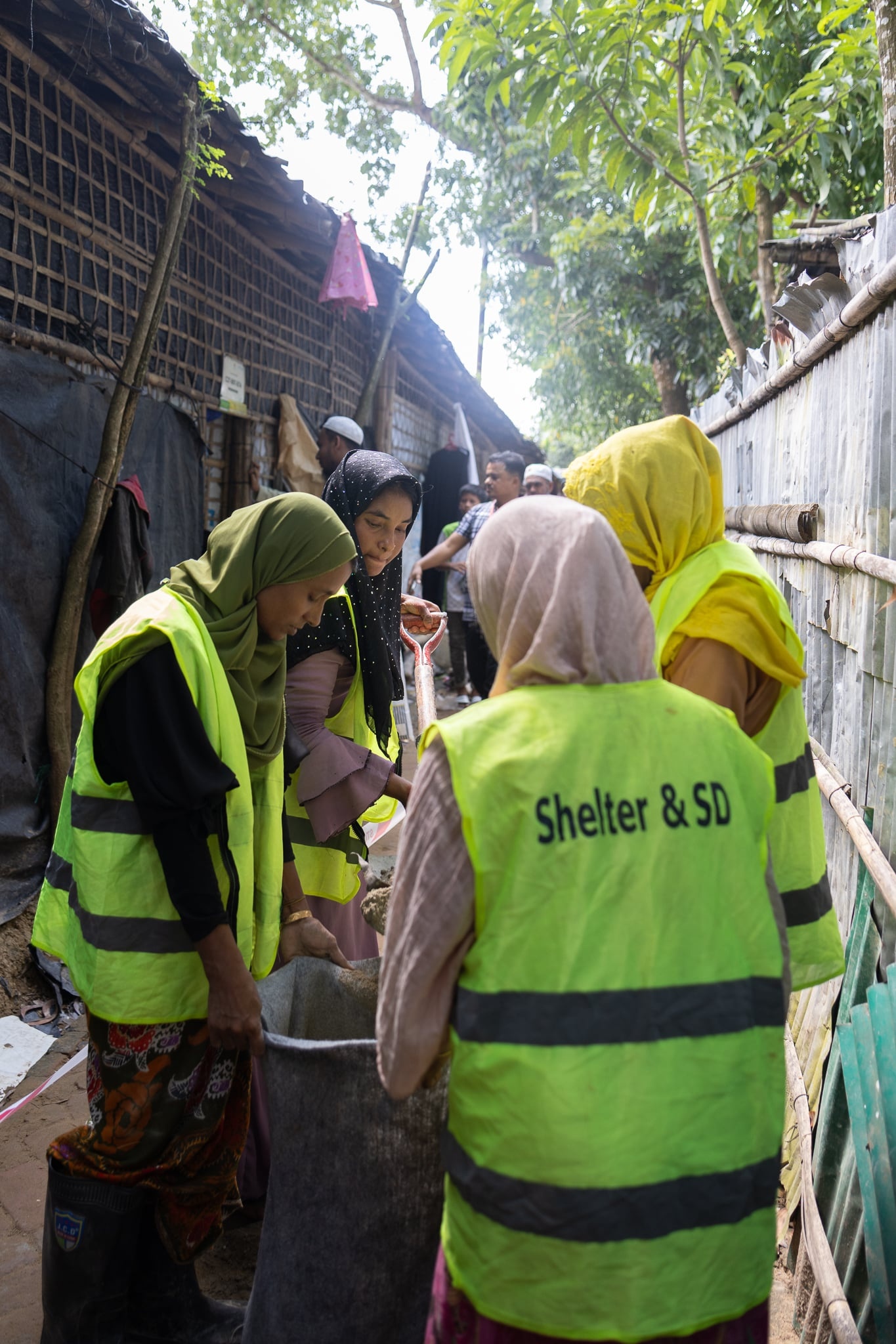 Rohingya refugee women in Cox's Bazar refugee camp working together to pave alleyways.