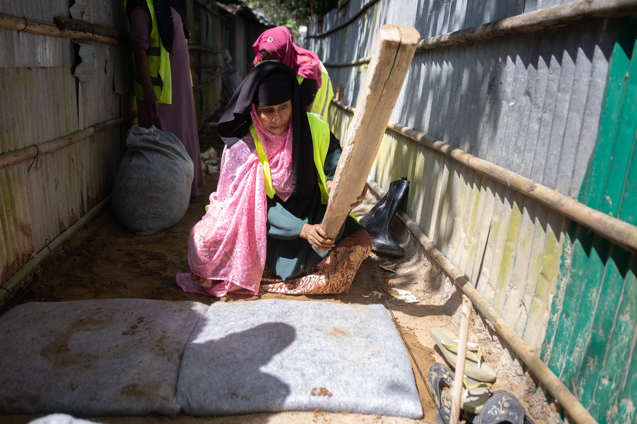 Rohingya refugee women in Cox's Bazar refugee camp working together to pave alleyways.