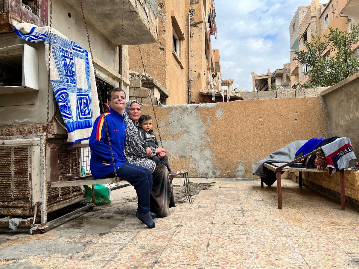 Kinda, 48, holds her grandson Nasr, while she and her son, Mohamad, sit together on the iron swing at their home in Deir-ez-Zor city, Syria.  