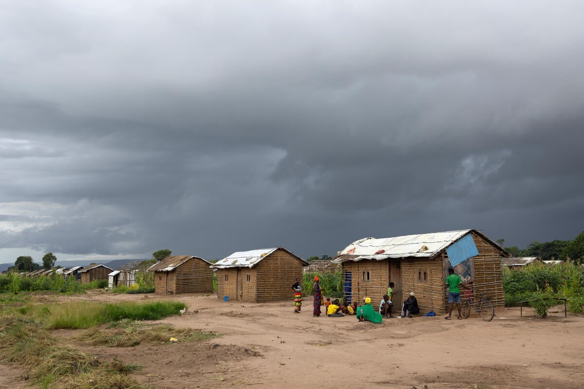 A settlement of shelters on arid land under a stormy sky