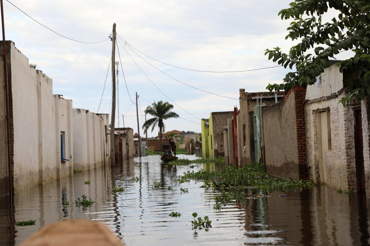 A man navigates down a flooded residential street in a wooden boat.