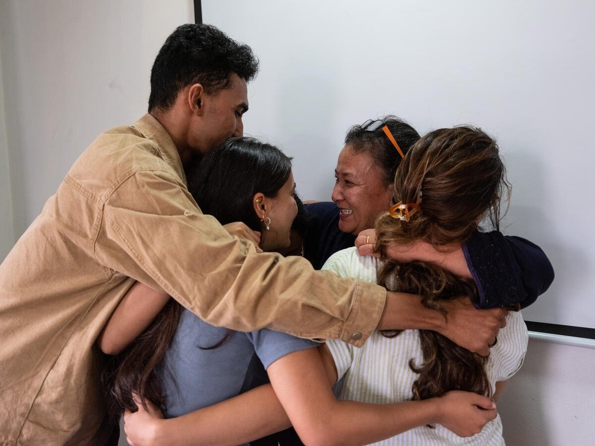A man and three women embrace, smiling.