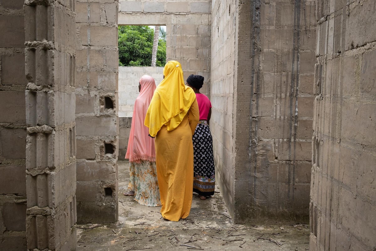 Three women walk through an abandoned building with their backs to the camera.