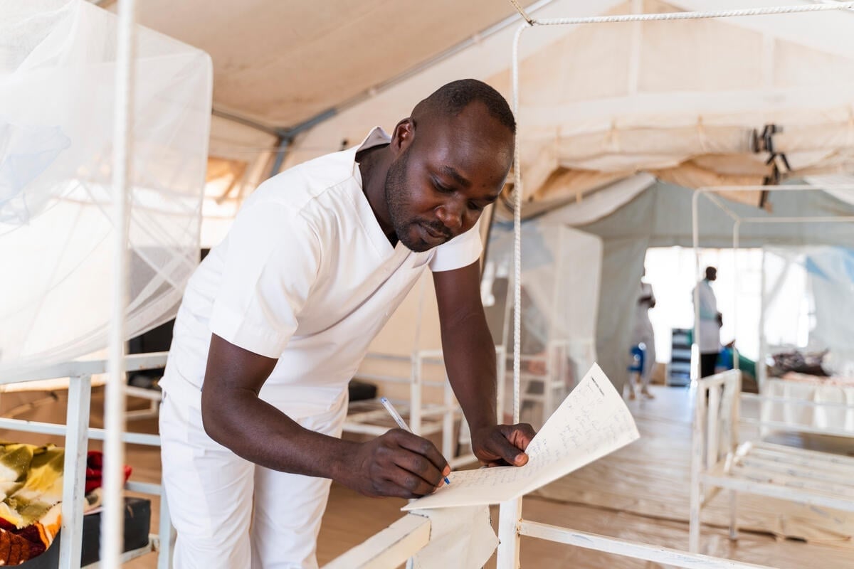 A male nurse in uniform writes down information on a piece of paper in a hospital