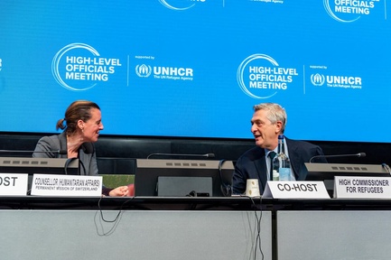 A woman and a man face each other at the podium.