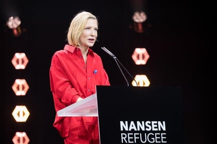 Cate Blanchett stands behind a podium which reads "Nansen Refugee Award"