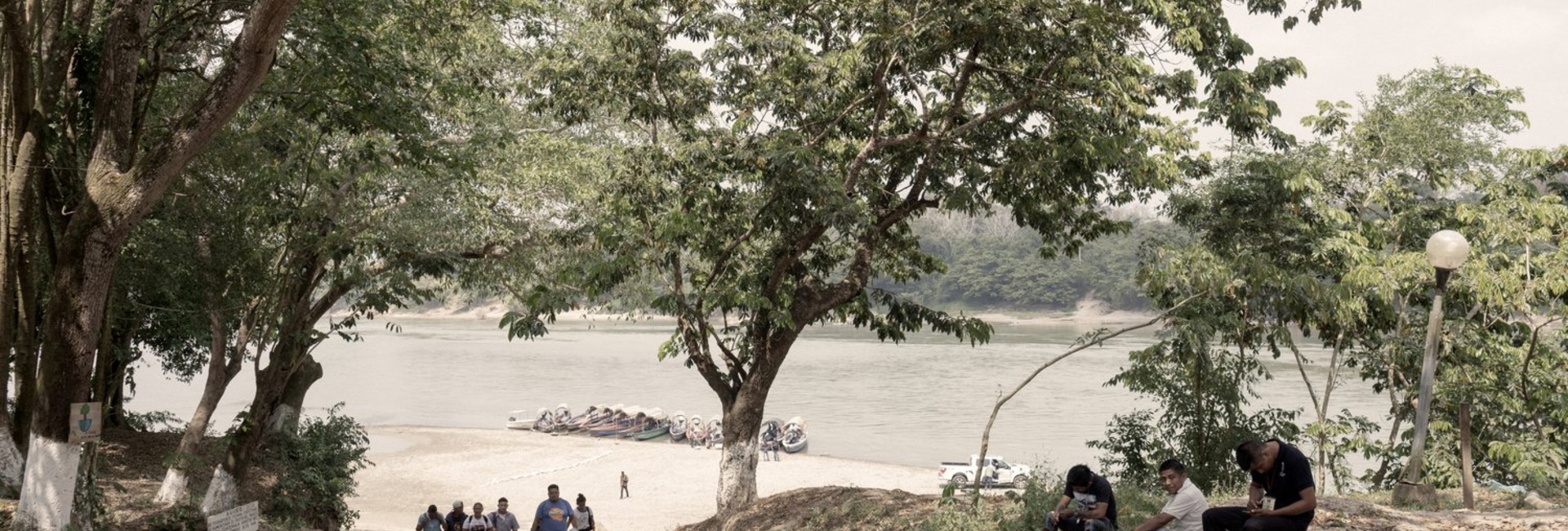 A group of people walk away from a river bank.