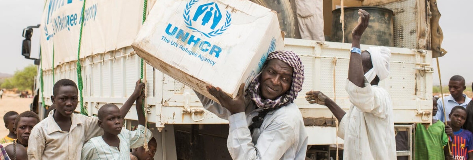 UNHCR staff unload boxes of emergency supplies from a truck in a refugee camp. 